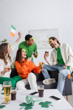 amazed woman pointing at bearded friend with sticky note on forehead while playing guess who game on Saint Patrick Day