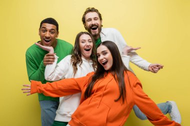 Excited interracial friends having fun on yellow background  clipart