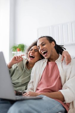 Laughing african american couple watching comedy movie on laptop at home 