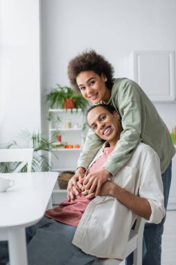 Smiling african american woman holding hands of boyfriend at home 