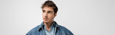 stylish young man in denim clothes looking away isolated on grey, banner 