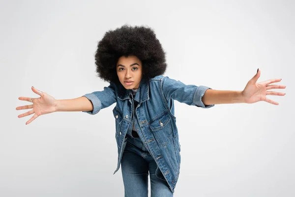 Young african american woman in jeans and denim clothes looking at camera isolated on grey
