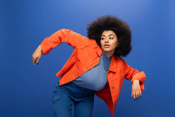Curly African American Woman Bright Orange Jacket Looking Away Blue — Zdjęcie stockowe