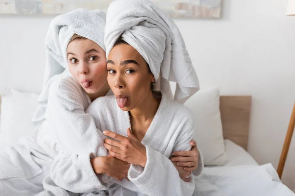 Young Interracial Women White Towels Bathrobes Looking Camera Sticking Out — Stock fotografie