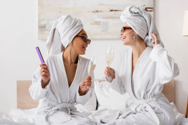 Щасливі Міжрасові Жінки Махрових Халатах Стильних Сонцезахисних Окулярах Тримають Шампанське — стокове фото