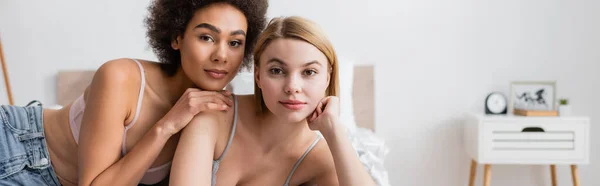 stock image young multiethnic women in lingerie looking at camera in bedroom, banner