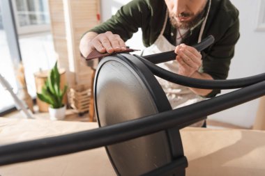 Cropped view of bearded restorer sanding chair on table in workshop 