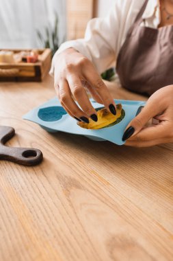partial view of african american woman holding silicone mold and soap bar in craft workshop