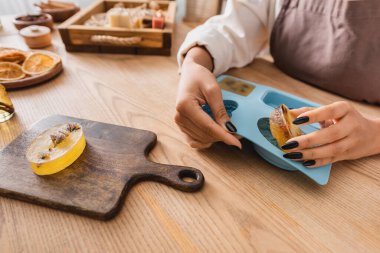 cropped view of african american woman taking soap bar off silicone mold near chopping board on wooden table