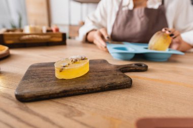 selective focus of herbal soap on chopping board near cropped african american woman with silicone mold on blurred background