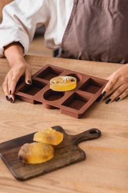 partial view of african american craftswoman near natural homemade soap on silicone mold and chopping board in workshop