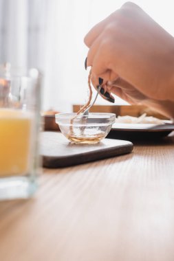 cropped view of african american woman dipping twine in melted wax while making candle wick in craft workshop