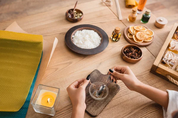 partial view of african american woman making candle wick near wax sheets and natural ingredients in craft workshop