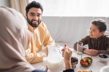Gülümseyen müslüman baba ve oğul Suhur 'daki tesettürlü bulanık kadına bakıyor. 
