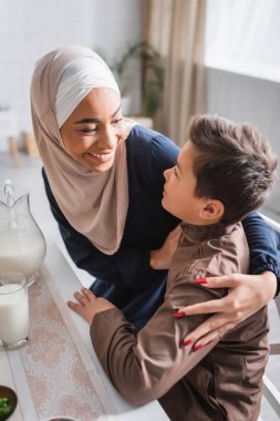 Gülümseyen Afro-Amerikan annesi Ramazan 'da oğlunu kucaklıyor. 