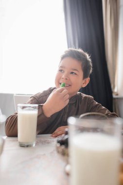 Smiling muslim kid holding cevizli sucuk near ramadan breakfast at home  clipart