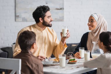 Gülümseyen Orta Doğulu aile evde ramazan kahvaltısı yaparken konuşuyor. 