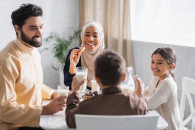 Ramazan sabahı ailesinin yanında cevizli sucuk tutan tesettürlü Afro-Amerikan kadın. 