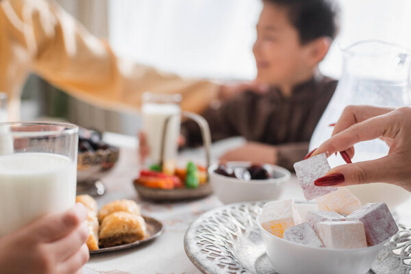 Мусульманская женщина держит турецкий восторг рядом с сухур пищи и размытые семьи дома 