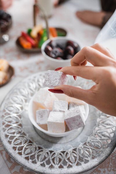 Cropped view of muslim woman holding turkish delight during ramadan morning 