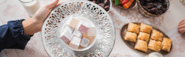 Top view of muslim woman holding plate with turkish delight during suhur and ramadan, banner 