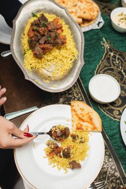 Evde iftar sırasında tabakta pilav servis eden Müslüman kadının üst görüntüsü 