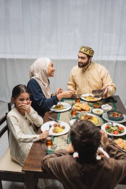 Müslüman aileler çocukların yanında konuşuyorlar ve evde ramazan yemekleri yiyorlar. 