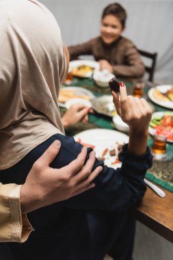 Muslim man hugging wife holding date fruit during iftar at home 