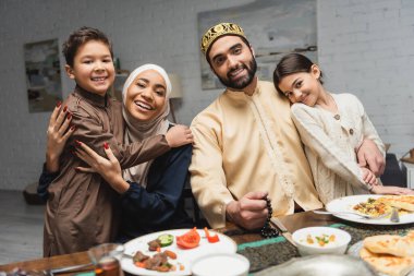 Orta Doğulu aile, evde ramazan yemeği sırasında çocuklara sarılıyor. 