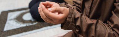 Cropped view of middle eastern boy praying at home, banner 
