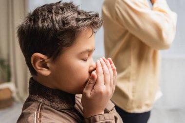 Muslim boy praying during salah and ramadan near dad at home 