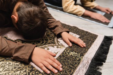 Arabian child praying on rug during ramadan salah at home 