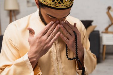 Middle eastern man with prayer beads doing salah at home 