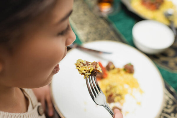 Blurred muslim girl eating pilaf during ramadan dinner 