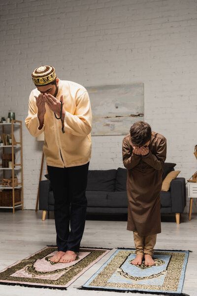 Босоногий ближневосточный мальчик и отец молятся во время молитвы дома 