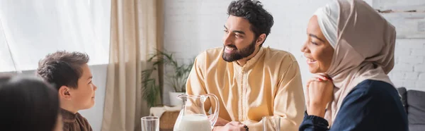 stock image Positive middle east parents looking at kids near milk at home, banner 