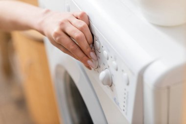 Evde çamaşır makinesinin düğmesine basan kadın görüntüsü 