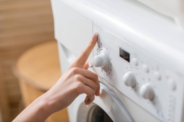 Çamaşır odasında çamaşır makinesinin düğmesine basan kadın görüntüsü  