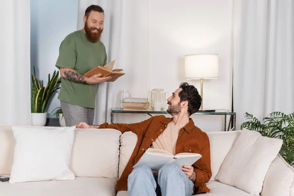 Positive Gay Couple Holding Books While Resting Modern Living Room —  Fotos de Stock