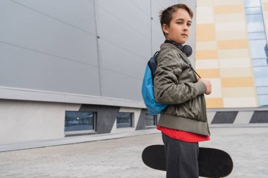 Kablosuz kulaklıklı çocuk sırt çantalı ve alışveriş merkezinin yakınında bir pano tutuyor. 