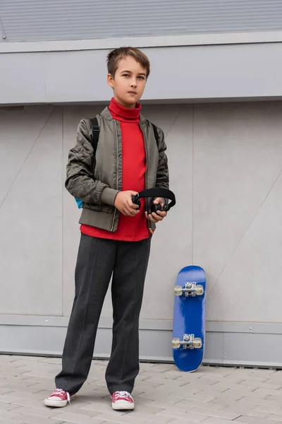 Preteen Boy Bomber Jacket Holding Wireless Headphones While Standing Penny — Zdjęcie stockowe
