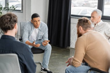 African american man with alcohol addiction sharing problem during group therapy session in rehab center  clipart