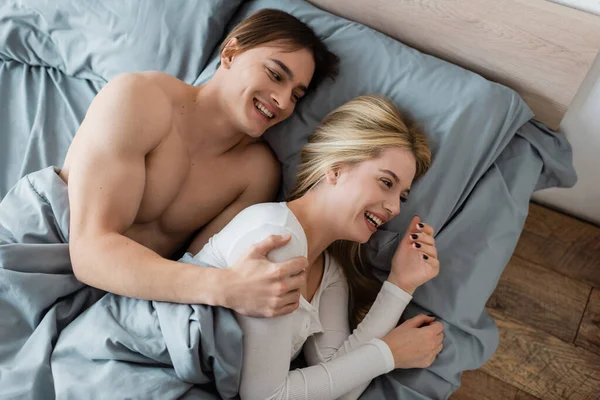 stock image top view of shirtless man hugging and laughing with blonde woman after one night stand 