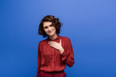 Minnettar dil öğretmeni, kısa kıvırcık saçlı, göğsüne sarılan mavi tenli. 