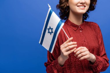 İsrail bayrağı taşıyan gülümseyen İbrani öğretmenin mavi üzerine izole edilmiş görüntüsü.