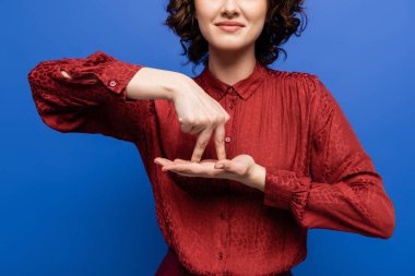 partial view of positive teacher showing gesture meaning stand on sign language isolated on blue clipart