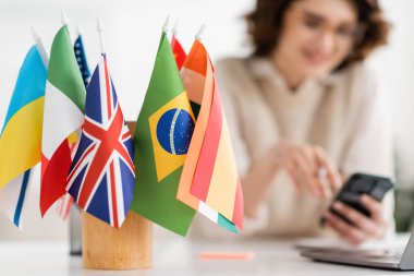 international flags of different countries near language teacher on blurred background  clipart