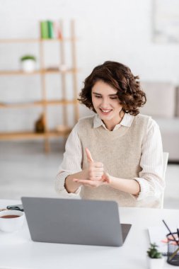 positive teacher showing help word on sign language during online lesson at home clipart