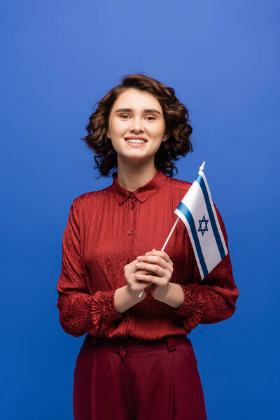 cheerful teacher of Hebrew language holding flag of Israel isolated on blue  