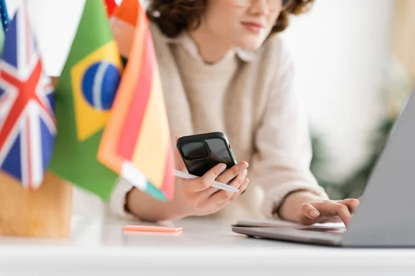 Cropped View Language Teacher Using Mobile Phone Laptop Different Flags — Stock Photo, Image